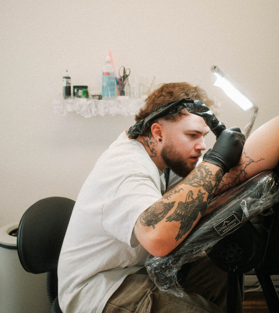 Tattoo artist tattoing a client's arm